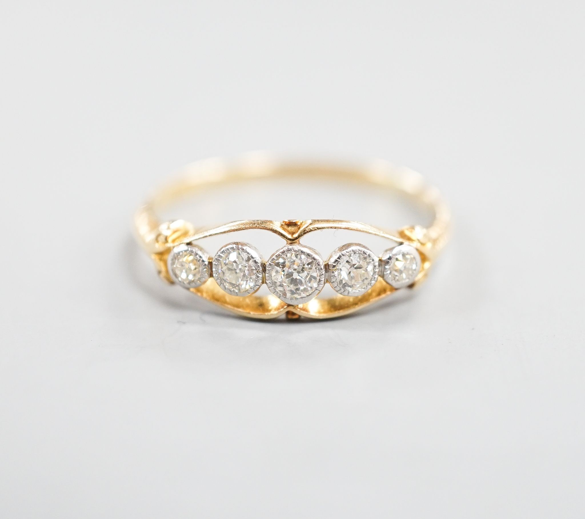 An 18ct and graduated five stone millegrain set diamond ring, size U/W, gross 2.6.